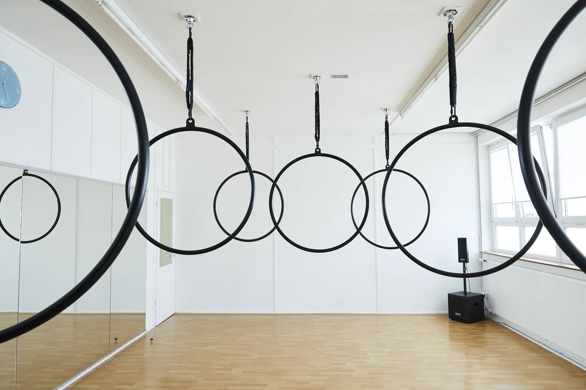 Reihe schwarzer Aerial Hoops, die im Studio von der Decke hängen