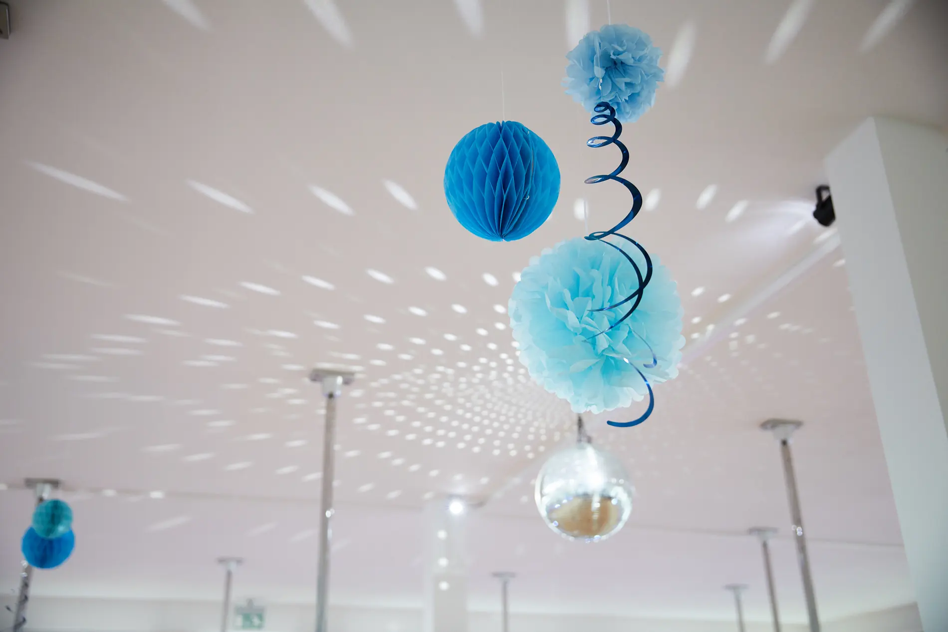 Blaue Pompons und Spiralen hängen von der Studiodecke