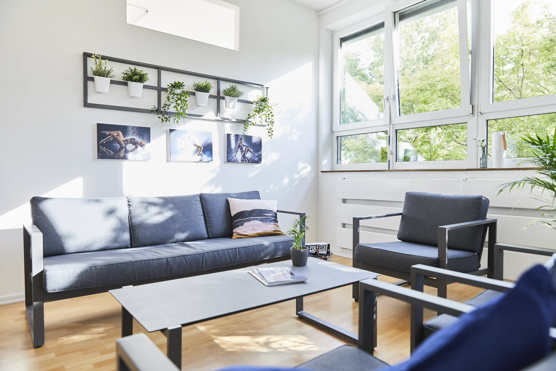 Lounge mit dunklem Sofa vor der Fensterfront