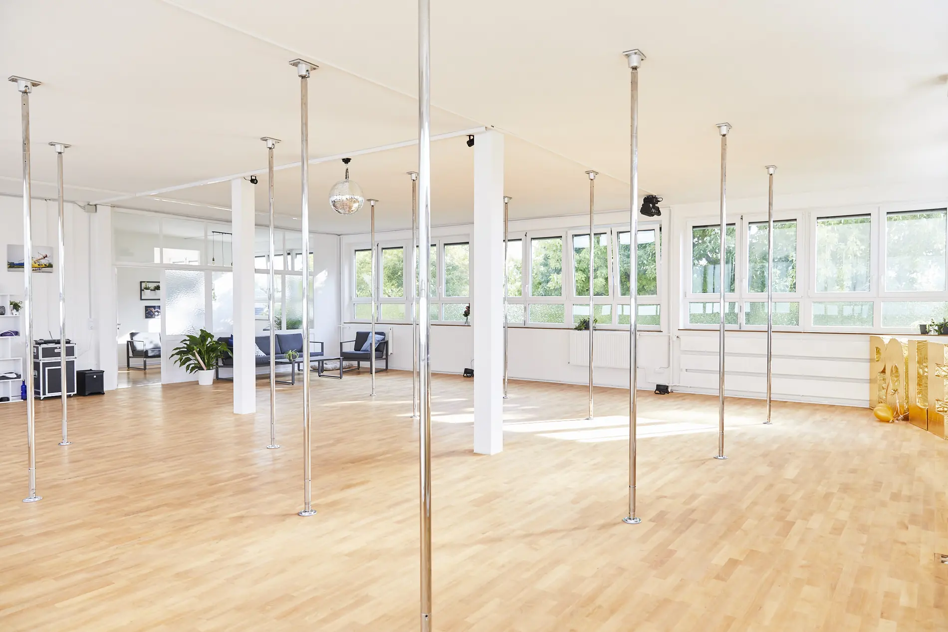 Großer Trainingsraum mit Pole-Stangen vor einer Spiegelwand