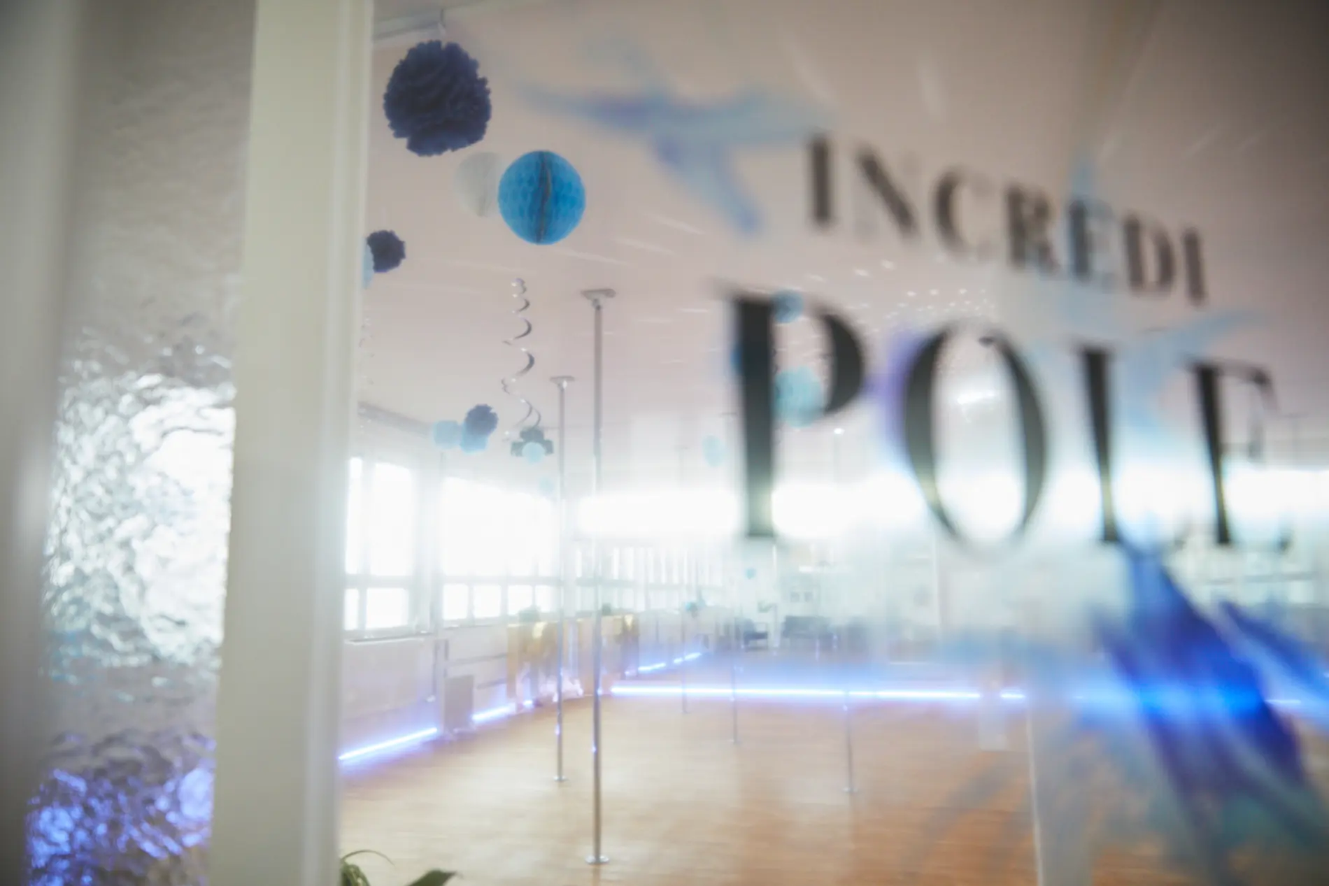 IncrediPOLE-Logo auf der Glaswand, Studio im Hintergrund